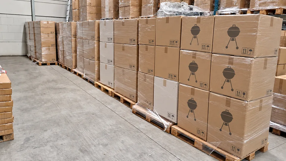 Een lange rij pallets met neutraal verpakte barbecues in een magazijn.